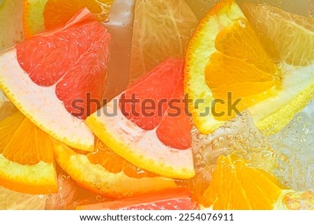 Slices of grapefruit, orange and pomelo in water on white background. Pieces of grapefruit, orange fruit and honey pomelo in liquid with bubbles. Slices of grapefruit, orange fruit and honey pomelo in