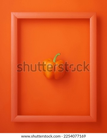 Bell pepper in wooden picture frame on orange background