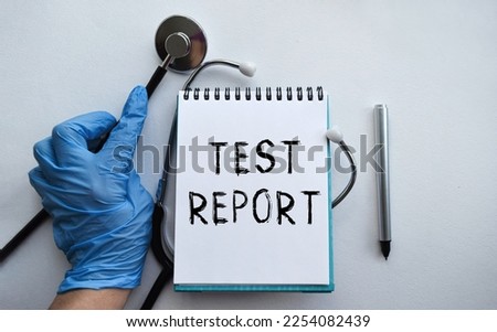 A doctor in blue medical gloves holds a notebook with the inscription TEST REPORT, on the background of a light table, along with a stethoscope.