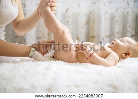 The mother is changing the baby's diaper. Selective focus. People.