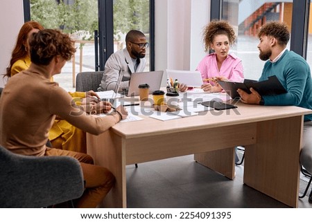 Successful cooperation of diverse business people gathered to work on joint project, sit talking, using laptops, discussing charts, plans, strategies, startups. business, success concept