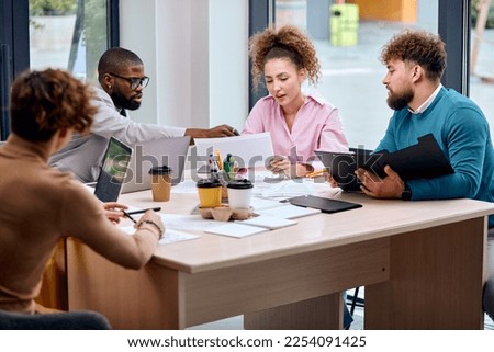 multi-ethnic team of colleagues in formal wear discussing business ideas while gathering at table in modern office and working together, successful collaboration of multi-ethnic group of people