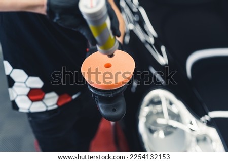 Close-up shot of professional buffer tool being prepared to polish fresh car paintwork. Car detailing process. Horizontal indoor shot . High quality photo