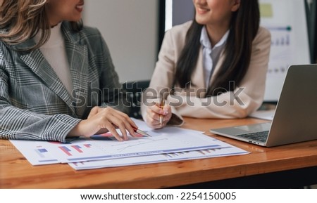 Two young pretty asia business woman in suit talking together in modern office workplace, Thai woman, southeast asian