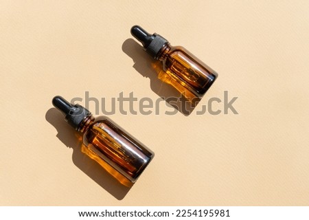 Top view of amber glass vials with cosmetic serum. Containers without labeling for cosmetics with dropper lids on beige background with hard shadow. Flatley, copyspace. Royalty-Free Stock Photo #2254195981