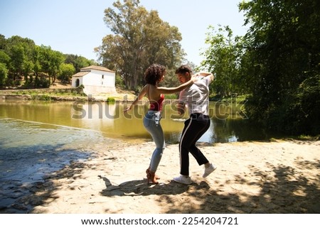 beautiful woman and handsome man latinos dancing bachata are dancing by the river in the forest. The couple do different postures while dancing. Dancing concept and expressions. Royalty-Free Stock Photo #2254204721