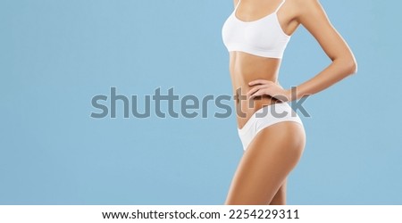 Young, fit and beautiful brunette woman in white swimsuit posing in studio. Concept of fitness, dieting and skin care.