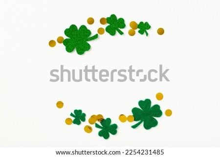 St Patrick's Day concept. Creative layout with frame of four-leaf clover and gold coins on white background. Flat lay, top view.