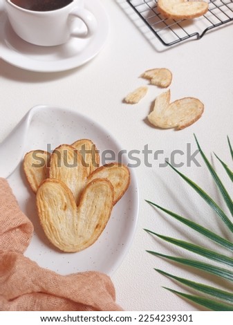 original pie biscuits or palmier biscuit french cookies made from puff pastry or elephant ear or french hearts cookie or puff pastry and honey double whirl or butterfly cookies. served on white plate.