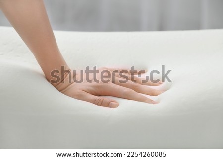 Woman touching orthopedic memory foam pillow indoors, closeup Royalty-Free Stock Photo #2254260085
