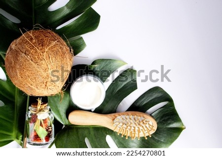 Coconut and cosmetic details on palm leaves standing on white background