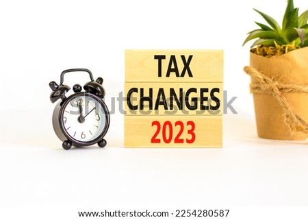 Tax changes 2023 symbol. Concept words Tax changes 2023 on wooden blocks on a beautiful white table white background. Black alarm clock. House plant. Business Tax changes 2023 concept. Copy space.