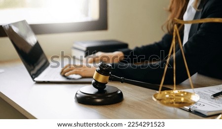 Male lawyer in the office with brass scale and using tablet and laptop on wooden table. justice and law concept in morning light

