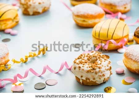 German Krapfen or donuts with streamers and confetti. Traditional Berliner for carnival and party.. Colorful carnival or birthday image
