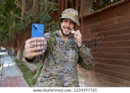Young hispanic man wearing soldier uniform make selfie by smartphone at park
