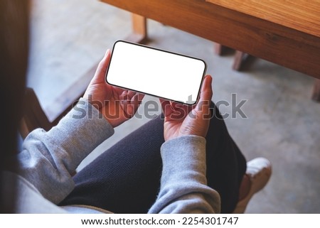 Top view mockup image of a woman using and holding mobile phone with blank screen