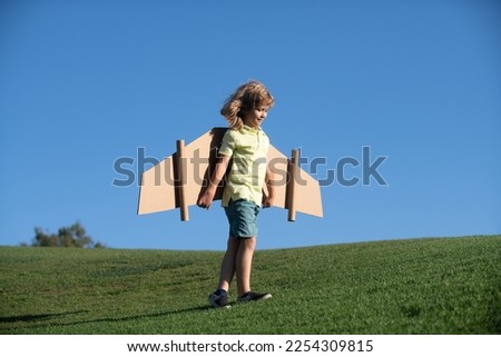Child to be pilot. Kid with paper wings flying. Summer vacation and travel concept. Funny child boy with toy cardboard airplane wings fly on sky. Startup freedom and kids carefree concept. Royalty-Free Stock Photo #2254309815