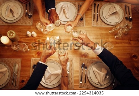 Champagne, glasses and cheers for celebration at a dinner for festive, new years eve or birthday. Party, event and top view of wine for a celebrating toast by a dining table at a restaurant or home. Royalty-Free Stock Photo #2254314035