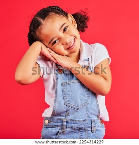 Happy, smile and cute young girl child portrait with red studio background with happiness. Smiling, youth and kid model with denim and adorable hands feeling girly, joyful and positive with fashion