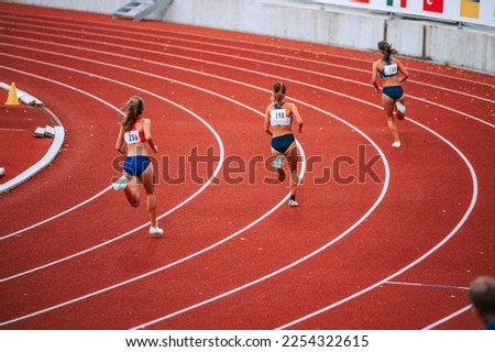Female athletes at the starting line of a 400m race on track, showcasing their focus and determination as they prepare to compete Royalty-Free Stock Photo #2254322615