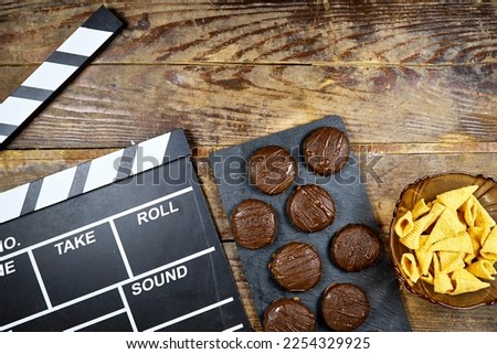 clapper board of video cinema with  cone corn chips with chocolate biscuit on wood table 
