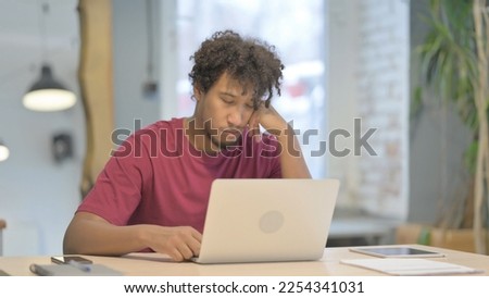 Tired Young African Man Sleeping while Working on Laptop