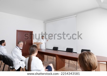 Doctor giving lecture in conference room with projection screen