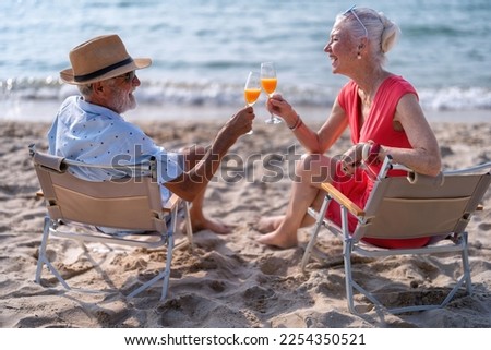 Couple old mature people on the sand at the beach sitting enjoying drink juice and living the moment Royalty-Free Stock Photo #2254350521