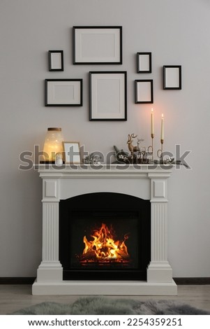 Stylish interior decorations on fireplace near white wall indoors