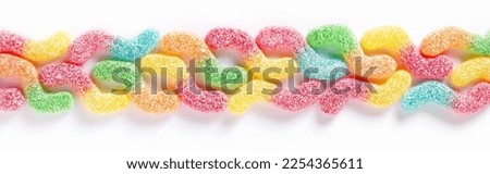 Sour tasting colorful gummy worms as line on white background, top view