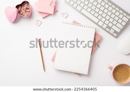 Valentine's Day concept. Top view photo of workspace planners pen keyboard pink sticky note paper heart shaped clips holder and cup of coffee on isolated white background with blank space