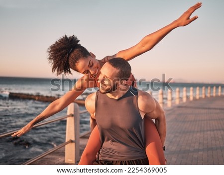 Beach, fitness and couple piggyback at sunset happy for summer holiday, vacation and quality time on weekend. Love, dating and black man and woman relax after exercise, workout and training by ocean Royalty-Free Stock Photo #2254369005