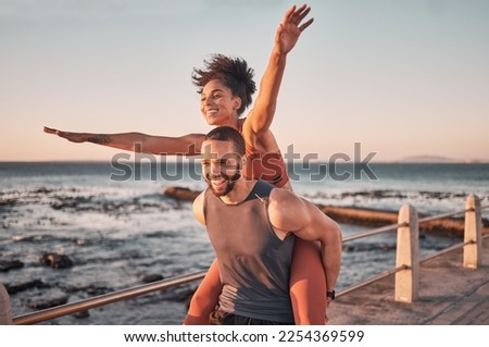 Sunset, relax and couple piggyback by ocean enjoying holiday, vacation and quality time on weekend. Love, freedom and happy black man and woman after exercise, fitness workout and training by sea Royalty-Free Stock Photo #2254369599