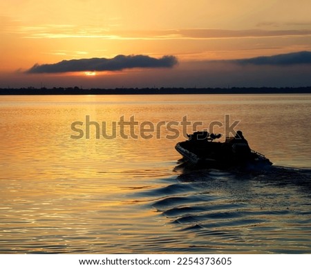 A Fisherman Heading Out in His Bass Boat for a Day of Fishing as the Sun Rises in a Beautiful Golden Sunrise Royalty-Free Stock Photo #2254373605