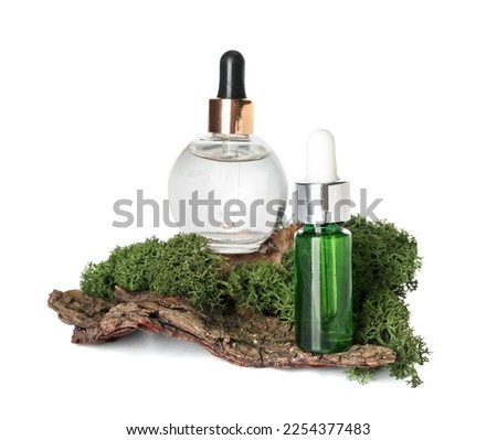 Cosmetic dropper bottles with green moss and tree bark on white background
