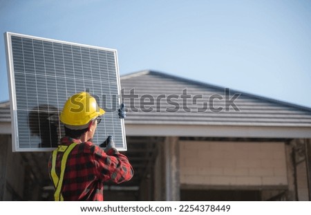 Engineer carrying solar panels Preparing to install on the roof of the house technician man with safety and protective gear installs solar panels on a roof. technician moving a solar panel