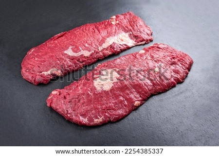 Raw wagyu bavette beef steak offered as close-up on rustic black board with copy space Royalty-Free Stock Photo #2254385337