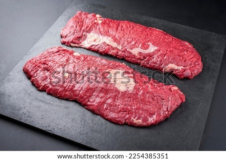 Raw wagyu bavette beef steak offered as close-up on rustic black board with copy space  Royalty-Free Stock Photo #2254385351
