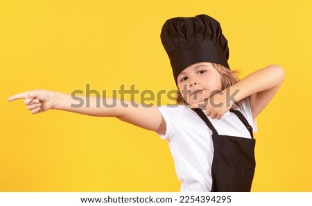 Excited chef cook. Child wearing cooker uniform and chef hat preparing food, studio portrait.