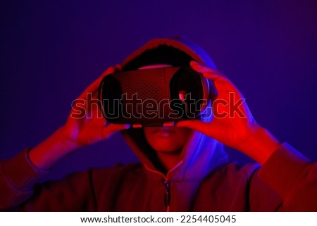 person wearing virtual reality glasses gets experience of gaming and entertainment. people in VR touches space with hands, blue and red light of abstract lamps. modern technologies of future