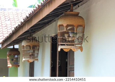 Bird cage with bird inside. Hanging in front of the house.