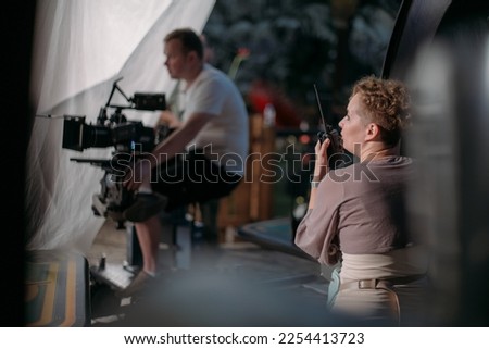 Director at work on the set. The director works with a group or with a playback while filming a movie, advertising, or a TV series. Shooting shift, equipment and group. Modern photography technique.