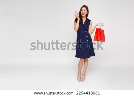Young beautiful Asian woman smiling, showing, presenting credit card and holding red shopping bags isolated on white background Royalty-Free Stock Photo #2254418061