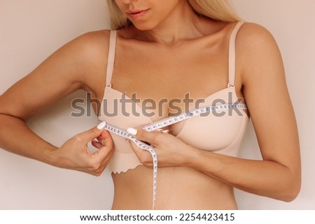 Cropped shot of young blonde slim woman measuring her measures the chest circumference with a centimeter isolated on a beige background. Diet, sport healthy lifestyle, wellness concept Royalty-Free Stock Photo #2254423415