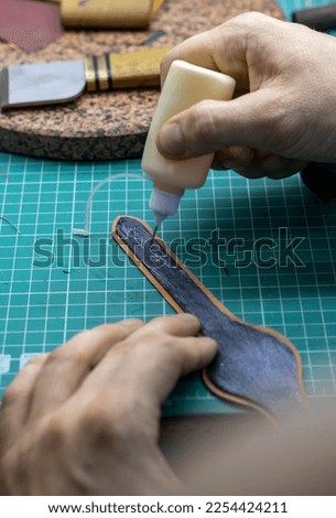 the master glues the details of the leather strap