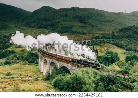 Jacobite steam train crossing the Glenfinnan Viaduct with steam rising from the chimney. Hogwarts Express, Harry Potter. Royalty-Free Stock Photo #2254429181