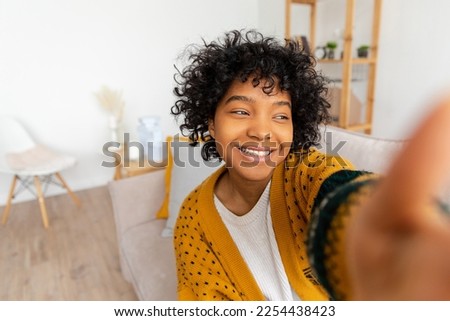 Happy african american teen girl blogger smiling face talking to webcam recording vlog. Social media influencer woman streaming making video call at home. Headshot portrait selfie webcamera view Royalty-Free Stock Photo #2254438423
