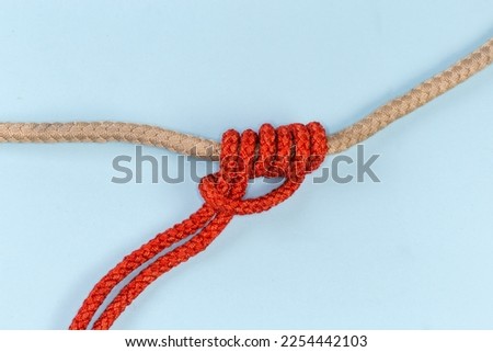 Rope Klemheist knot tied with an accessory cord on the main rope on a blue background
