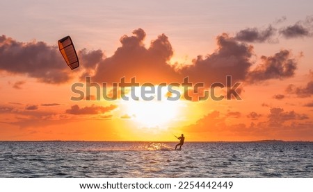 Sunset sky over the Indian Ocean bay with a kiteboarder riding kiteboard with a green bright power kite. Active sport people and beauty in Nature concept image. Le Morne beach, Mauritius Royalty-Free Stock Photo #2254442449