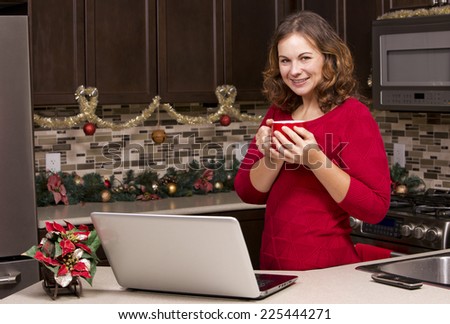 woman using laptop in the kitchen surrounded by christmas decorations